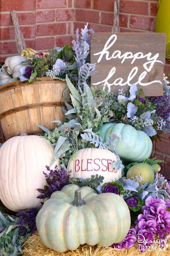 a lovely and lush fall arrangement of lots of pumpkins, greenery, bright blooms and a sign