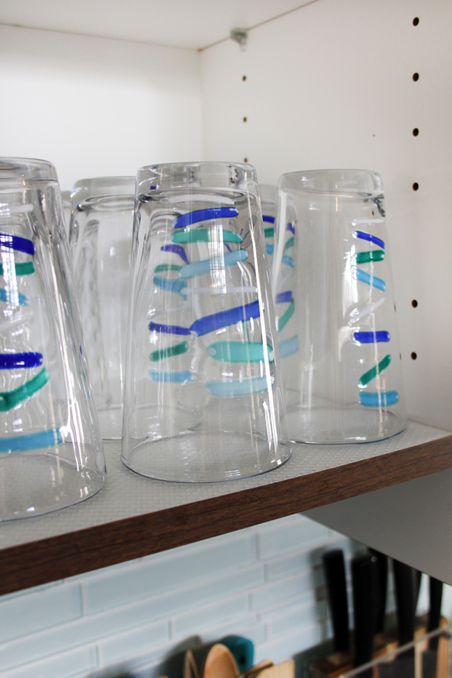 Shelf Liner Under Teal And Blue Striped Drinking Glasses