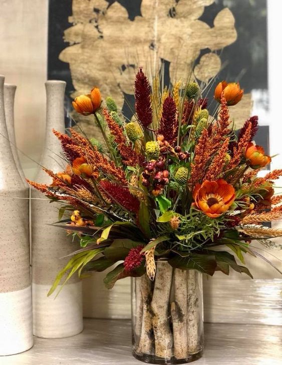 A Bright Rustic Arrangement Of Rust, Burgundy Faux Blooms, Dried Herbs And Greenery And Wooden Sticks In The Vase