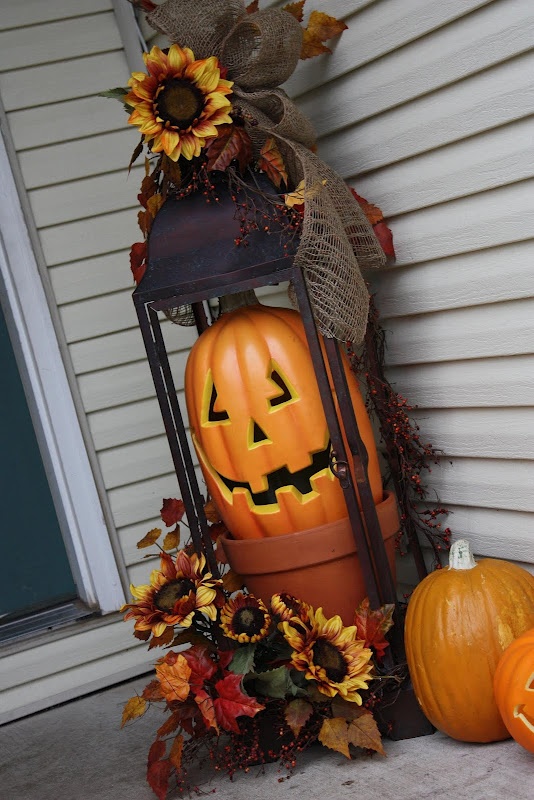 A Fall Outdoor Decoration Of A Large Lantern With A Faux Pumpkin, Faux Flowers And Pumpkins Is A Stylish Fall Idea