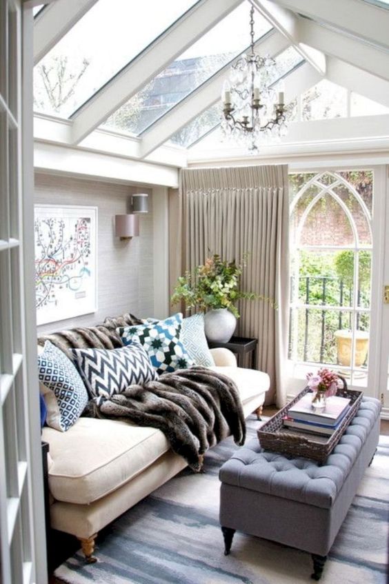 A Small Refined Sunroom With Elegant Furniture, Lots Of Pillows, A Fir Throw, A Vintage Chandelier And Neutral Curtains