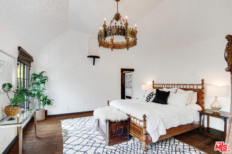The Master Bedroom Is Done With A Gorgeous Chandelier, A Wooden Chest And A Chic Bed