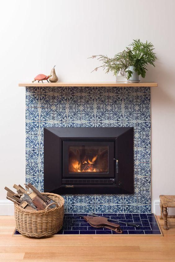 a built-in fireplace surrounded with blue printed tiles and navy ones looks ultimately chic and very elegant