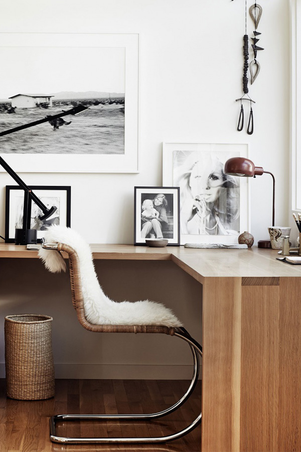 A Scandinavian Home Office Nook With A Floating Corner Desk, A Gallery Wall, A Rattan Chair And A Basket Plus Some Faux Fur
