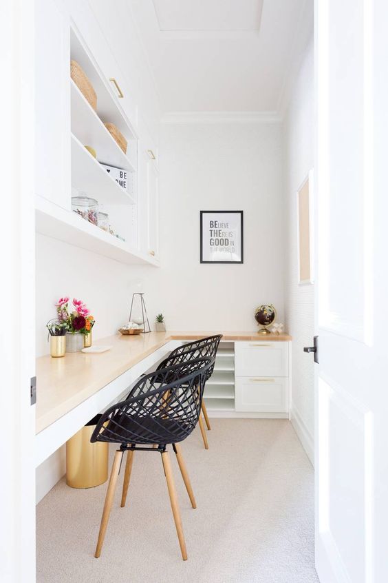 A Tiny White Home Office With A Shared Corner Desk And Cabinets Under The Surface, A Large Open Cabinet And Black Woven Chairs