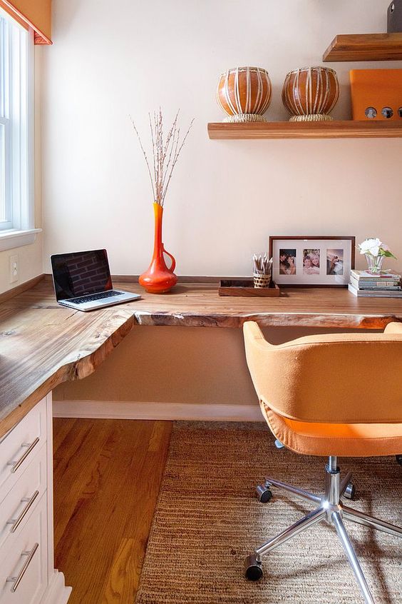 A Warm-Colored Home Office With A Live Edge Corner Desk, A Yellow Chair, Open Shelves And An Orange Vase