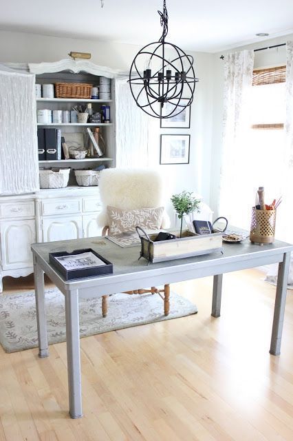 A Modern Farmhouse Home Office With A White Storage Unit, A Pale Desk, A Vintage Sphere Lamp And Faux Fur
