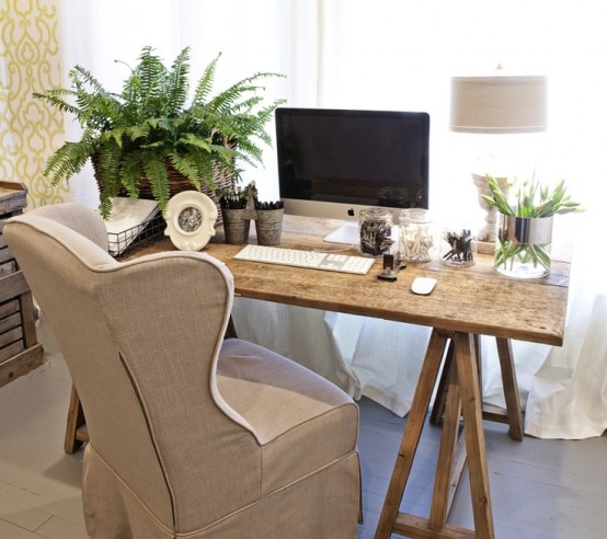A Small Rustic Home Office With A Trestle Desk, A Burlap Chair, Potted Greenery And Lamps Is A Cozy Space