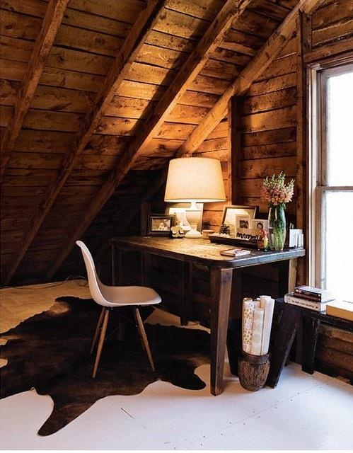 A Rustic Attic Home Office With A Wooden Desk, Chair, Lights, Lamps And Photo Frames And Blooms Is Very Cozy