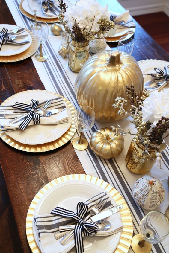 A Chic Rustic Thanksgiving Tablescape With A Striped Runner, Gold Chargers, Striped Napkins, Gilded Pumpkins And Faux Branches