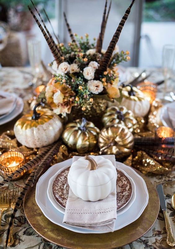 A Vintage Boho Thanksgiving Tablescape With Printed Linens And Plates, Gold Chargers, Cutlery, Pumpkins And Candleholders, Feathers And Blush Blooms