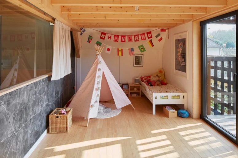 The Kid's Room Features A Bed, A Teepee, Some Bold Art And Garlands And An Entrance To The Balcony