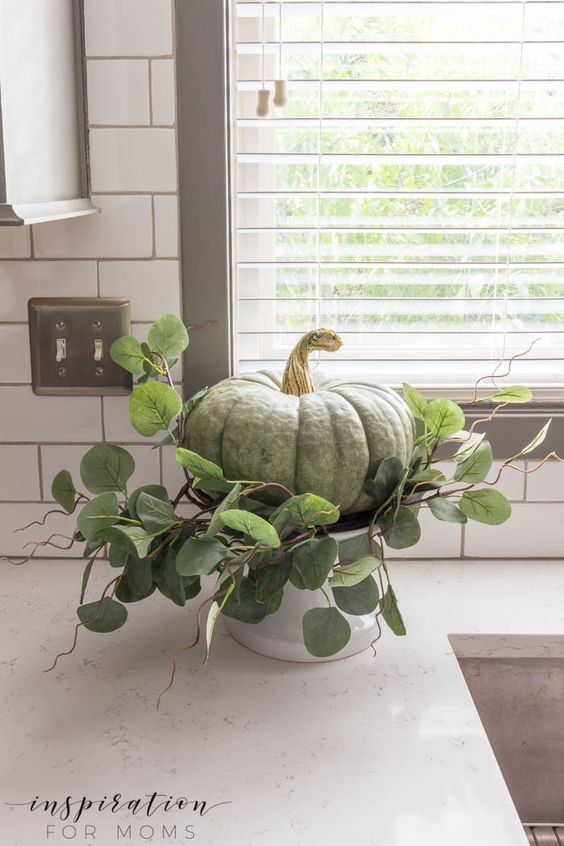 A Green Heirloom Pumpkin With Greenery On A Stand For Rustic Thanksgiving Decor
