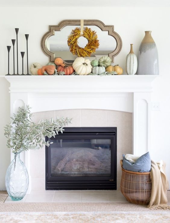 A Stylish Modern Thanksgiving Mantel With A Leaf Wreath, Neutral And Pastel Pumpkins And Large Vases